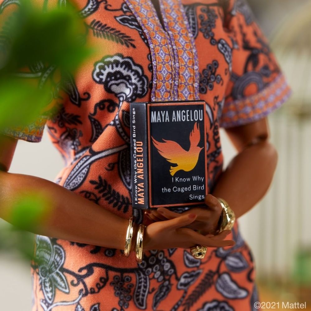Barbie Maya Angelou: detalhe da capa do livro em miniatura que vem com a boneca, de capa preta com detalhes em cores quentes e título em branco.