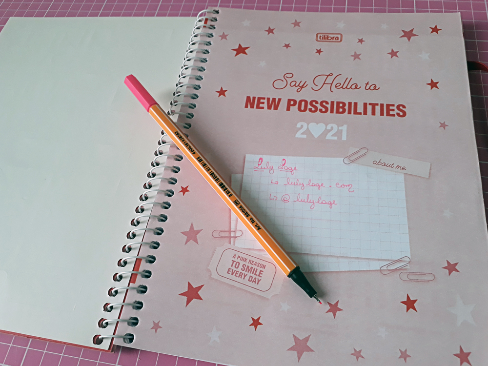 Imagem do My Pink Planner 2021 aberto na folha de rosto, onde se lê em inglês "Diga Olá para novas possibilidades" em vermelho num fundo rosa. Em baixo dos dizerem existe um quadrado branco para informações pessoais à escolha de quem usar o produto.