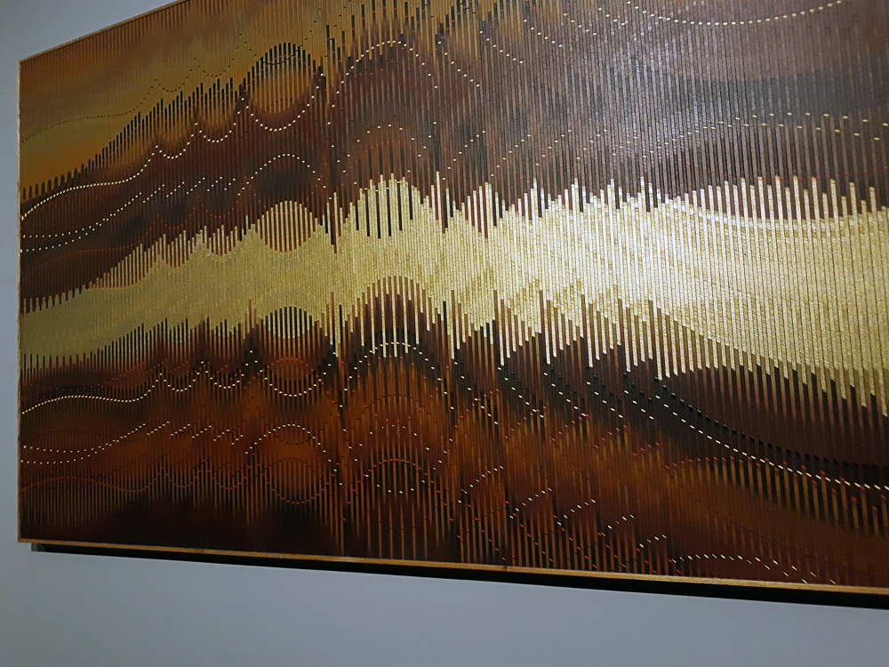 Quadro em tons terrosos e metálicos, onde o uso de linhas de diferentes espessuras formando ondas e picos possibilitam efeitos de ilusão de ótica.