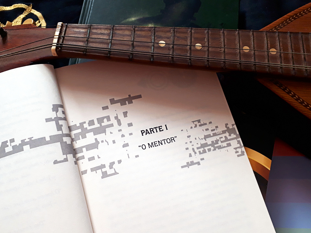 Página inicial da primeira parte do livro, onde se lê 'Parte 1 - O Mentor', como elementor quadrados ao redor dando sensação de pixels. O Instrumento está levemente em cima do canto superior da página.