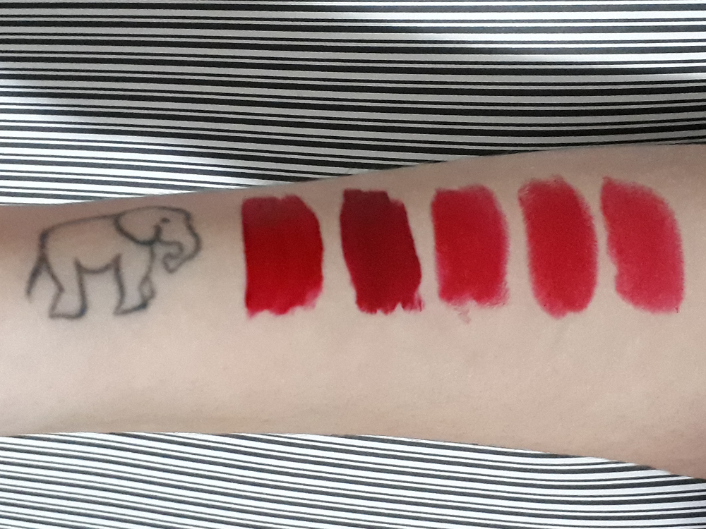 Braço de cor clara com uma tatuagem de elefante e swatches dos 5 batons descritos no post lado ao lado, ao longo dele em frente a ela.