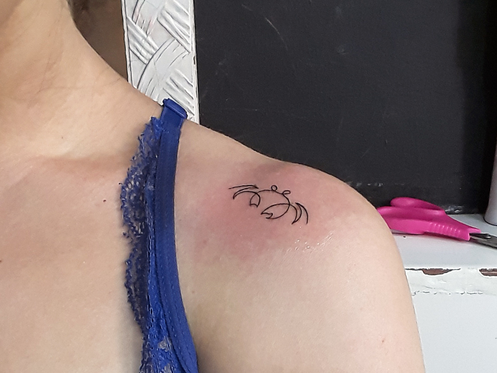 Foto da tatuagem de caranguejo, recém feita, com a região do ombro ainda vermelha.