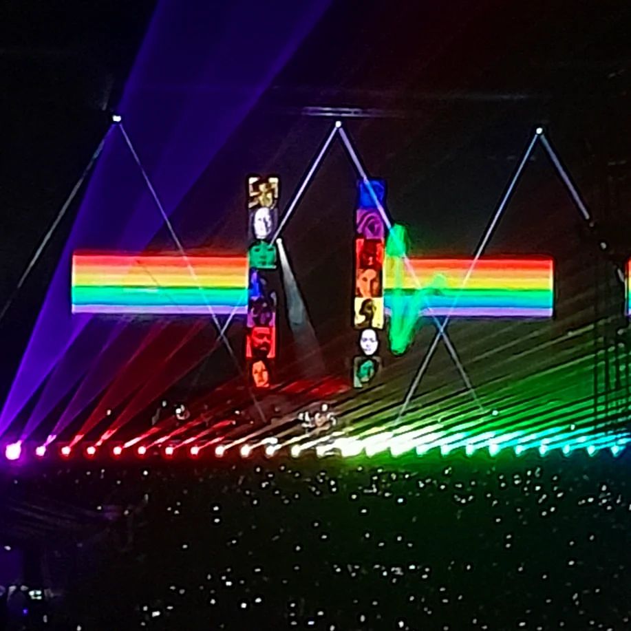 Palco na música Brain Damage, com grandes prismas no palco e luzes das cores do arco-íris saindo em direção à plateia