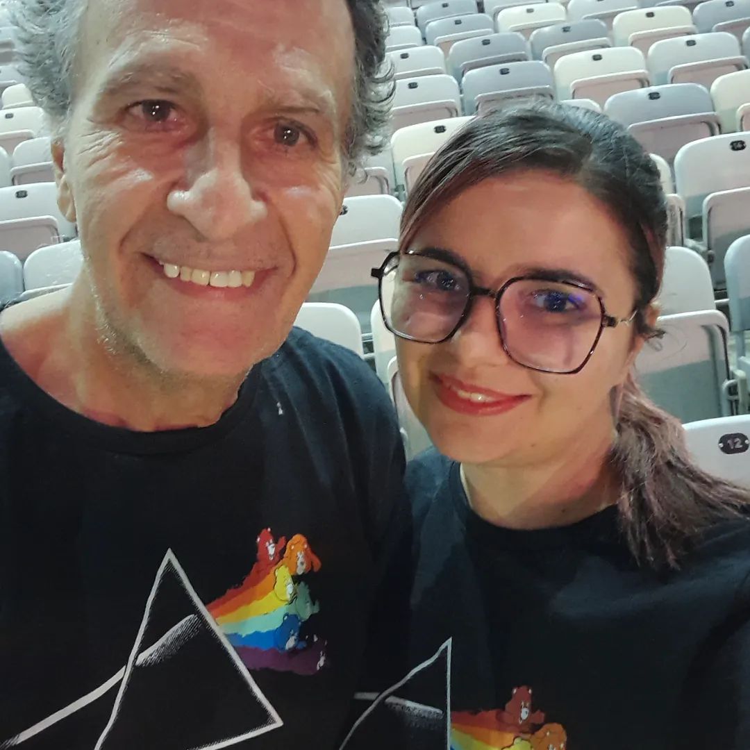 Fotos de duas pessoas, meu pai e eu, sorrindo para a câmera, usando blusas idênticas onde o prisma de Pink Floyd, um feixo de luz se transformando em um arco-íris, termina com os Ursinhos Carinhosos saindo das cores.