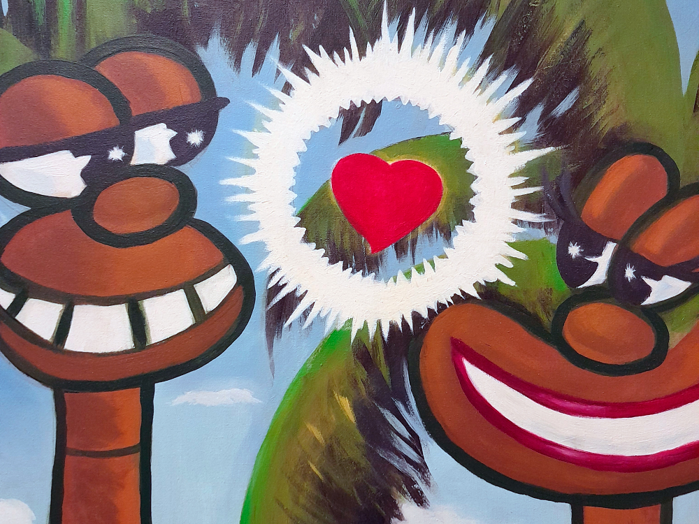 Pintura em estilo pop com dois personagens de pele marrom e traços caricatos, com grandes sorrisos e óculos escuros. Entre eles, um coração vermelho dentro de um halo branco luminoso. As figuras são humanóides, com fisionomia de coqueiros, e o fundo azul complementa a atmosfera tropical da imagem.