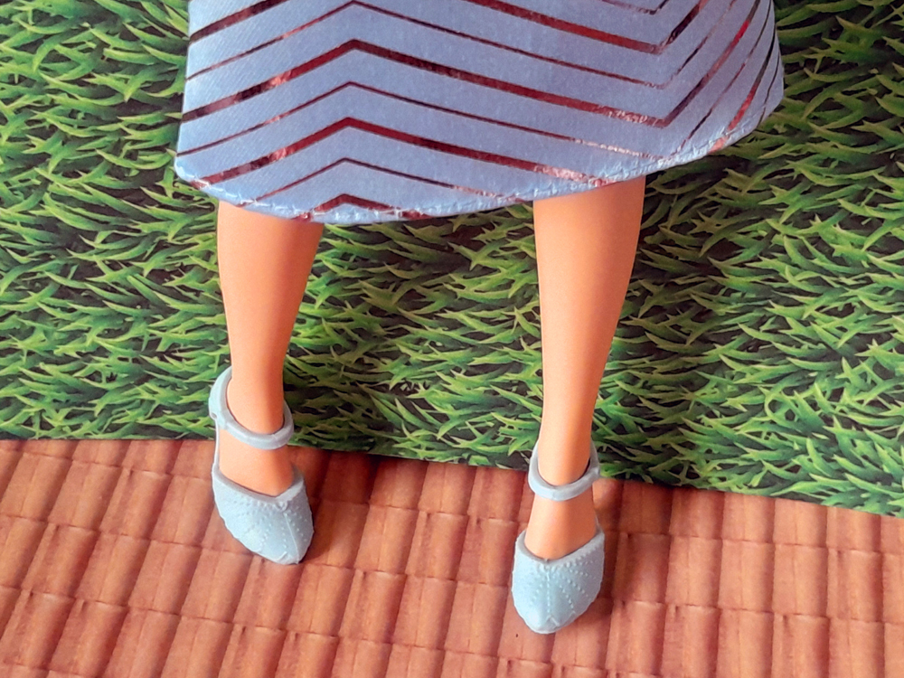 Detalhe das pernas e sapatos da boneca usando sapatos azul-claro combinando com o uniforme da Universidade Shiz.