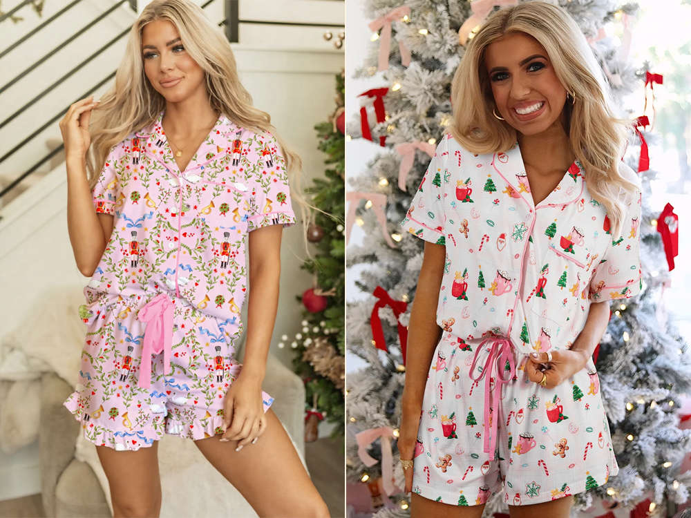 Imagem de uma mulher usando pijamas de Natal da loja Dear Lover com desenhos festivos em tons de rosa, vermelho e verde, sorrindo próximo a uma árvore de Natal decorada com enfeites vermelhos.