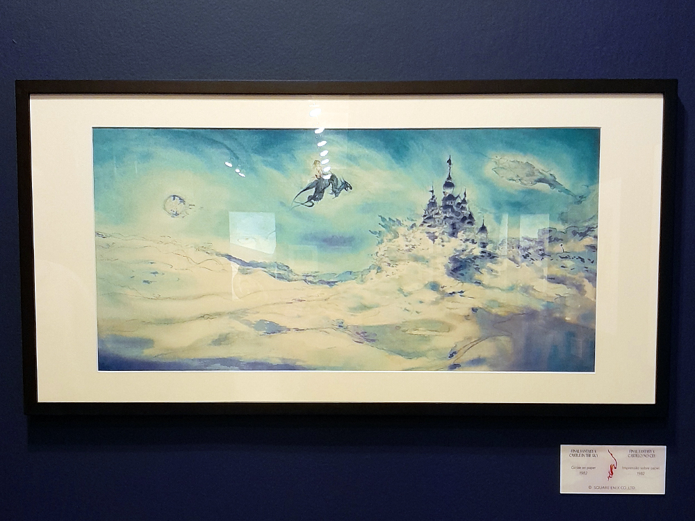 Ilustração de Yoshitaka Amano em tons azulados e claros, representando uma paisagem onírica com um castelo flutuante e uma figura montada em criatura alada, exposta em moldura preta sobre parede azul-escura.