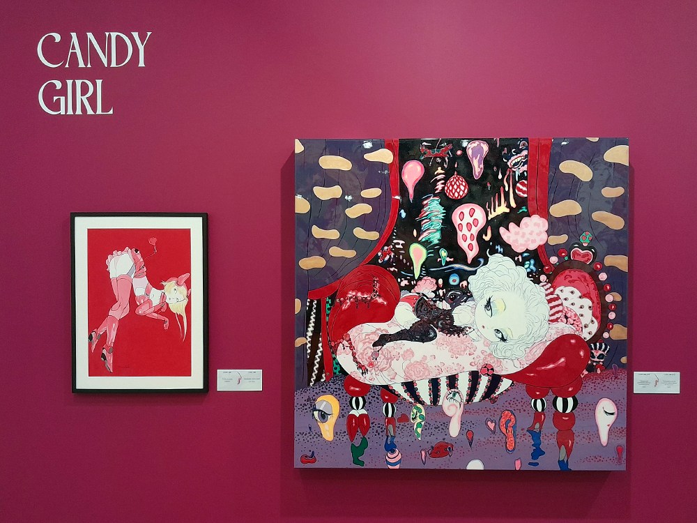 Vista geral da sala “Candy Girl” na exposição de Yoshitaka Amano no CCBB BH, com parede rosa e obras coloridas que misturam fantasia, erotismo e estética pop.