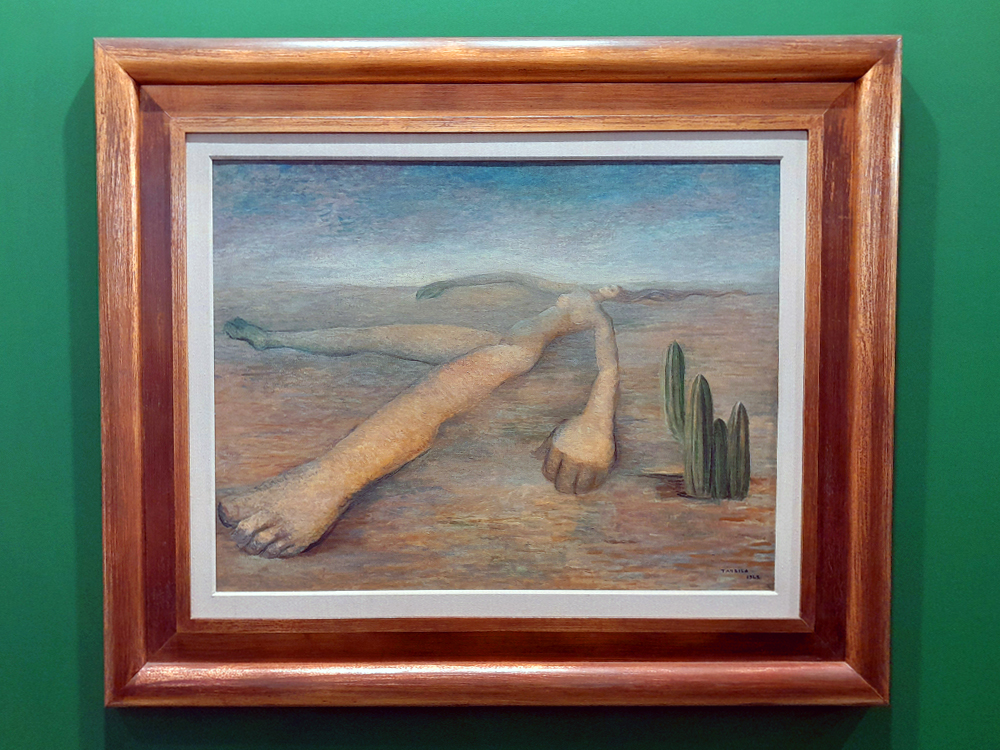 Pintura de Tarsila do Amaral retratando um cenário com uma pessoa deitada no chão e um cacto, em cores suaves.