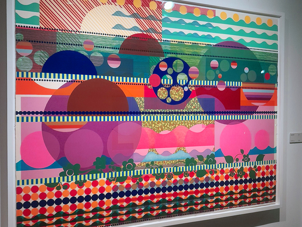 Obra de arte geométrica em grande formato. A composição reúne círculos, faixas, ondas e padrões coloridos em tons de rosa, azul, verde, laranja e amarelo, formando uma paisagem abstrata inspirada na natureza brasileira.