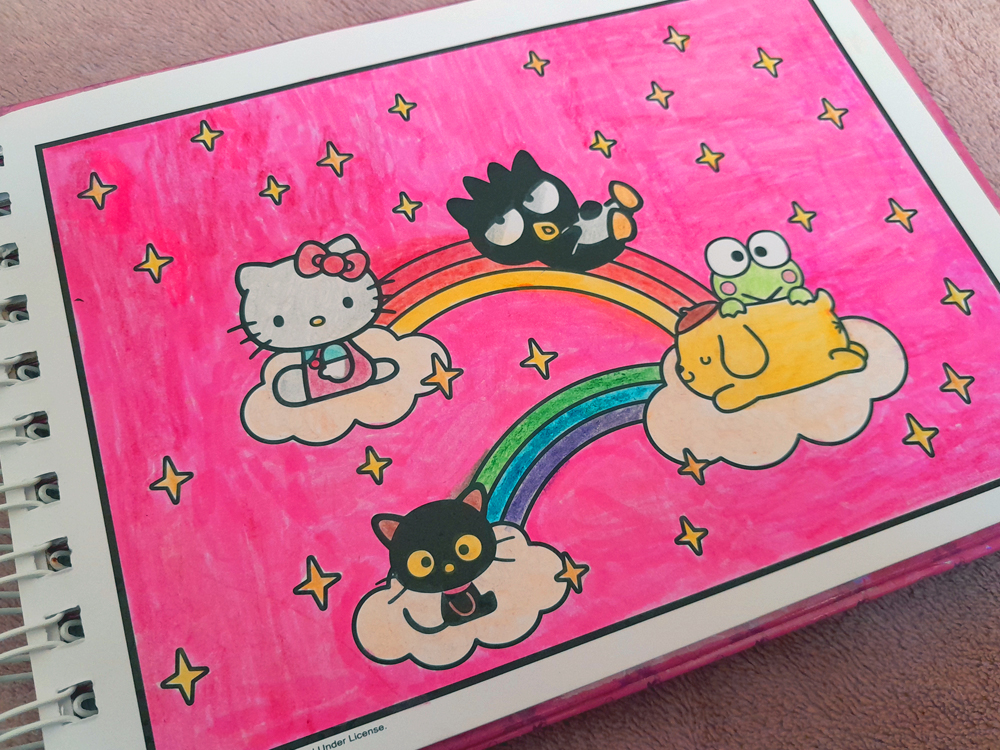 Página do livro de colorir da Hello Kitty finalizada com fundo rosa vibrante preenchido por marcadores. Hello Kitty, Badtz-Maru, Chococat, Keroppi e Pompompurin aparecem sentados sobre pequenas nuvens ligadas por um arco-íris colorido, cercados por estrelas amarelas.