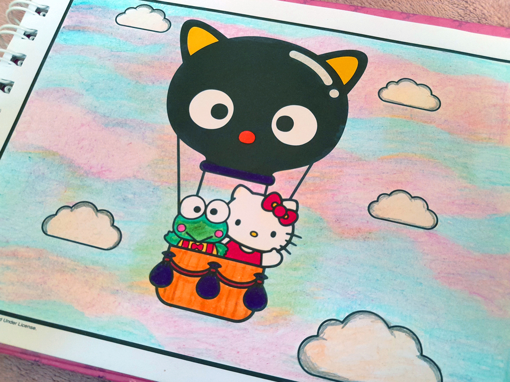 Ilustração colorida de Chococat pilotando um balão em formato de sua própria cabeça, levando Hello Kitty e Keroppi em um pequeno cesto laranja. O céu foi preenchido com um degradê suave em tons pastel de azul, rosa e lilás, criando um efeito delicado de aquarela, enquanto nuvens brancas completam a cena.