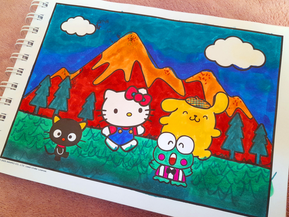 Páginas mostrando Hello Kitty segurando uma câmera fotográfica grande. A personagem está em destaque sobre um fundo magenta, cercada por estrelas amarelas, dentro de uma moldura roxa e laranja. A câmera recebeu tons de preto, cinza e roxo, enquanto os detalhes da imagem foram coloridos com marcadores em cores fortes e contrastantes.