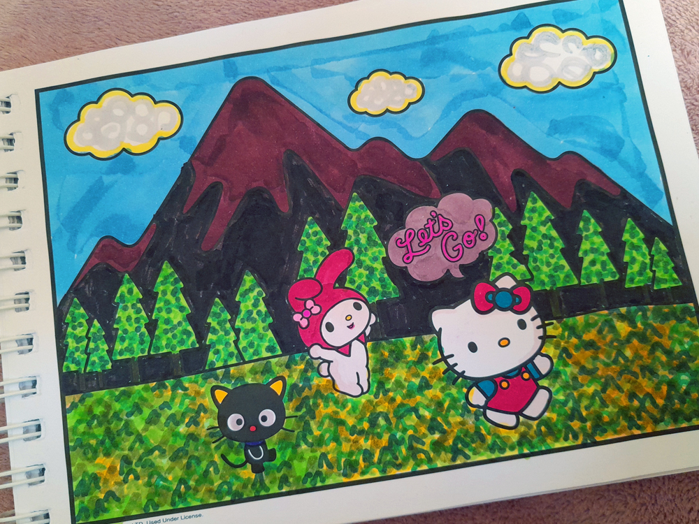 Página de livro de colorir mostrando Hello Kitty, My Melody e Kuromi correndo por uma floresta, com montanhas ao fundo. O céu é azul, as montanhas aparecem em tons de vinho, roxo e preto e as árvores têm diferentes tons de verde. O chão foi preenchido com uma textura intensa de pequenos traços em verde, amarelo e laranja. As personagens aparecem coloridas em seus tons característicos, e uma nuvem rosa ao fundo traz a frase Let’s Go!.